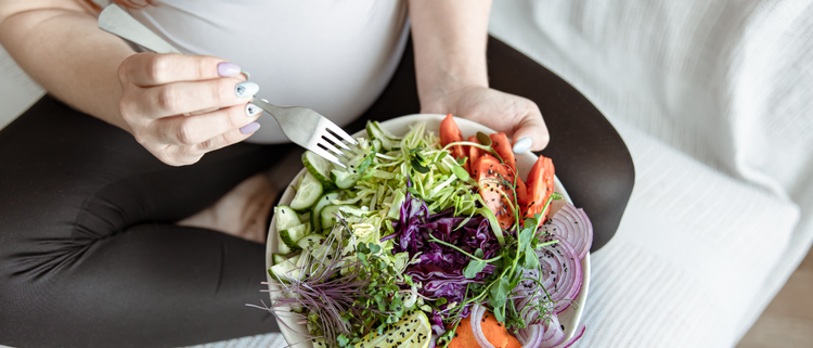 Blog of The Pre-Pregnancy Diet: Boost Fertility and Prepare Your Body for Baby which have image A pregnant woman in leggings and a white top sits with a colorful salad bowl, holding a fork.