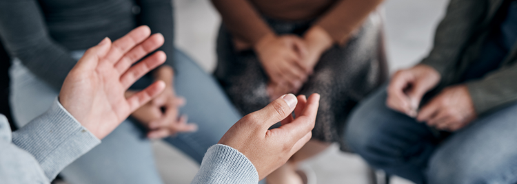 Blog of How Emotional Trauma Affects Your Cells and What You Can Do to Heal which have image A close-up of a person's hands gesturing while speaking in a support group or therapy session.